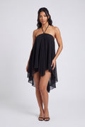 Robe noire fluide en mousseline, bretelles nouées au cou et ourlet asymétrique.
