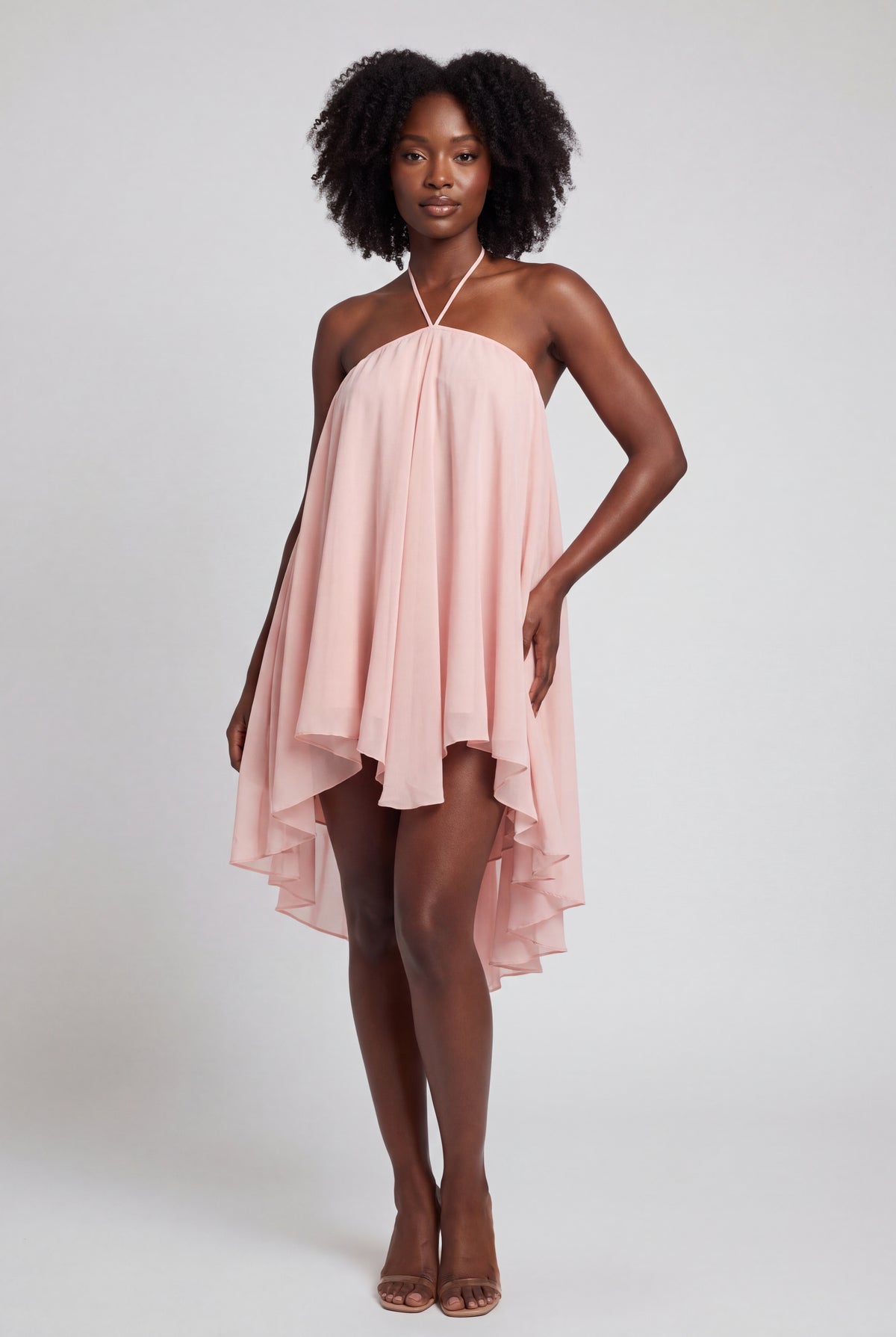 Robe rose fluide en mousseline, bretelles nouées au cou et ourlet asymétrique.
